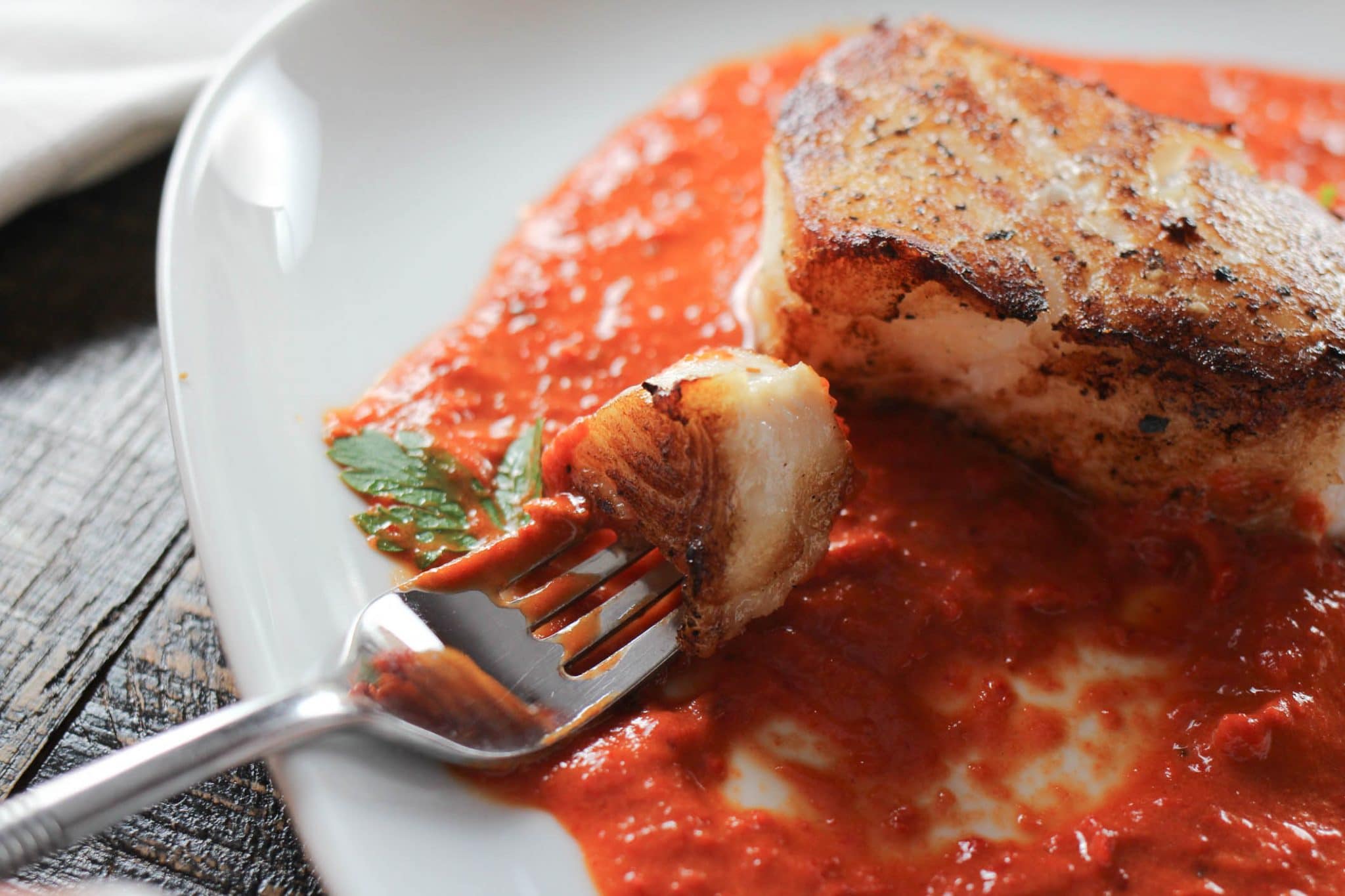 A perfectly seared Chilean sea bass with a spicy red pepper sauce.