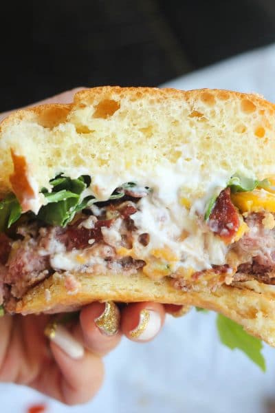 Meet the ultimate stuffed burger to rule your BBQ!!! This juicy stuffed burger oozes with melted cheeses and is topped with crispy bacon and peppery arugula