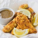Learn how to make incredibly crunchy baked chicken tenders that are uber flavorful and moist! I serve them with my multi purpose and super delicious Honey Mustard Dressing that makes these chicken tenders irresistible to adults and children!