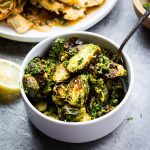 roasted brussels sprouts in a bowl with a spoon - Girl and the Kitchen