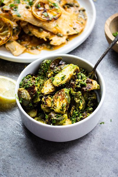 roasted brussels sprouts in a bowl with a spoon - Girl and the Kitchen