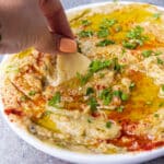 woman dipping pita into mediterranean eggplant dip