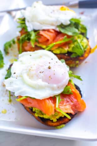a plate with avocado toast, a poached egg, and salmon