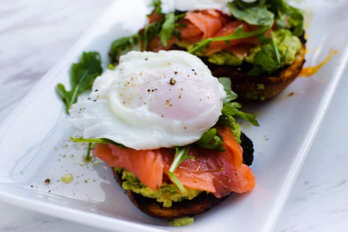 a plate with avocado toast, a poached egg, and salmon
