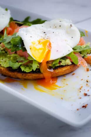 a plate with avocado toast, a poached egg, and salmon