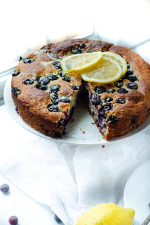 serving plate with French yogurt blueberry cake topped with lemon slices