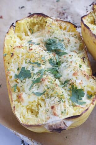 roasted spaghetti squash half with melted cheese and herbs